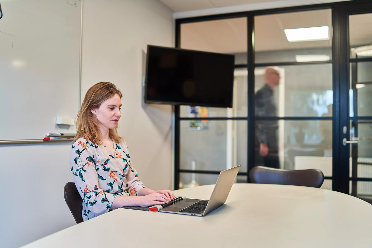 Woman working on a laptop with a RollerMouse Red in a meeting room