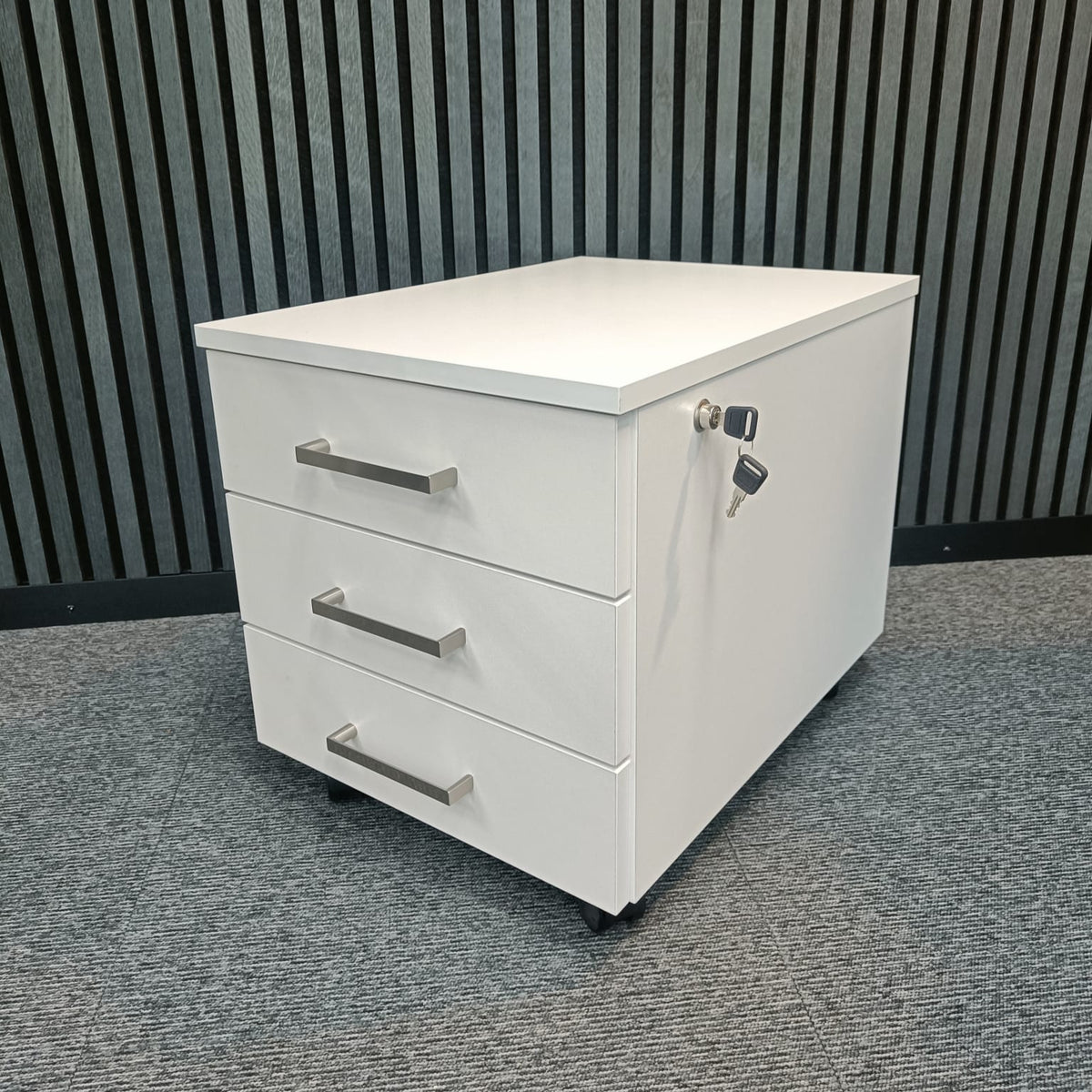 White three-drawer pedestal unit on castors, viewed at an angle