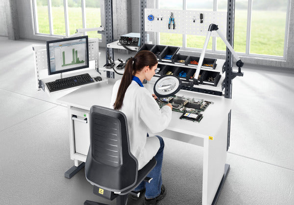 Laboratory worker seated on a Neon 2 ESD work chair at a bright workstation