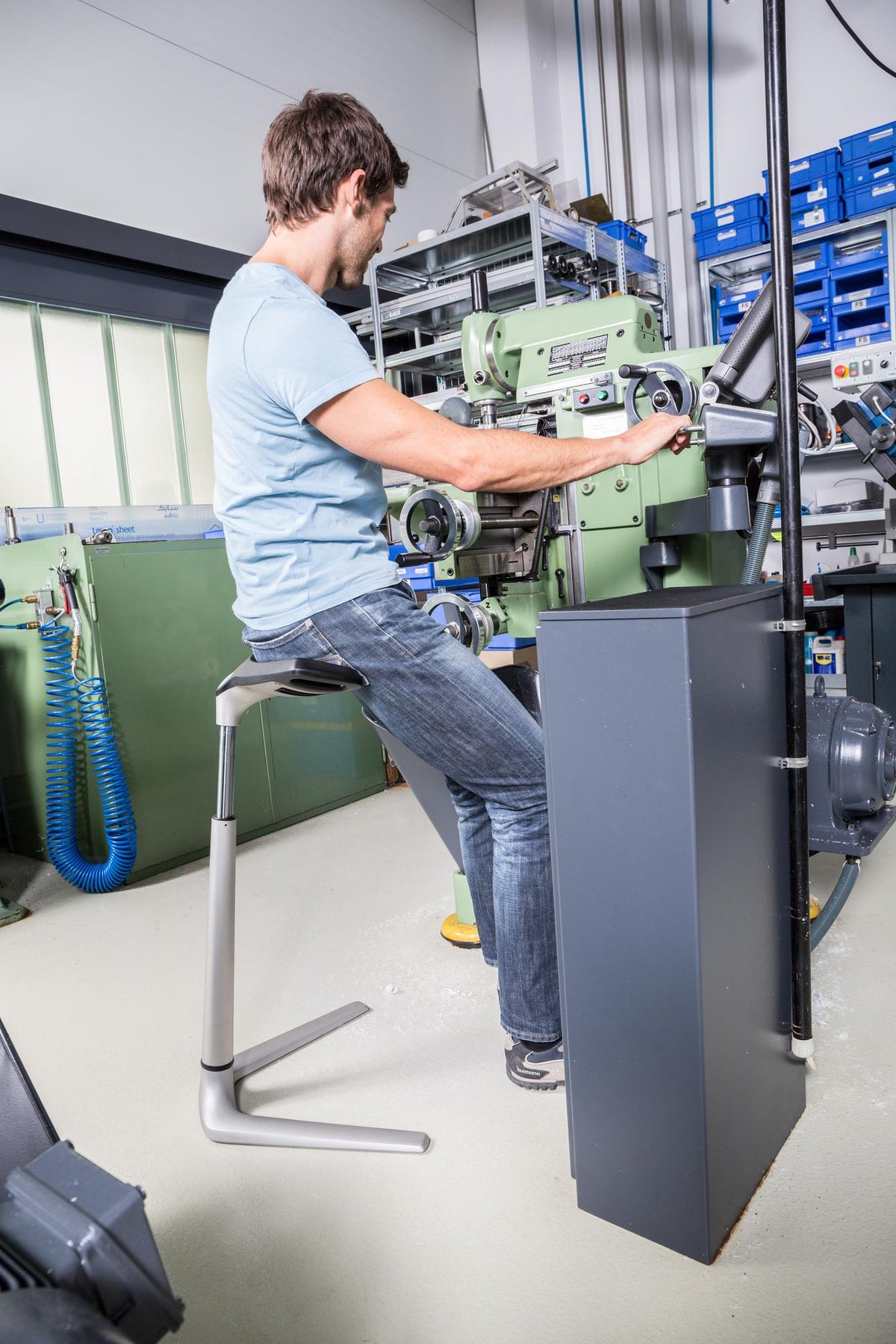 Technician leaning on a FIN chair while working at industrial machinery