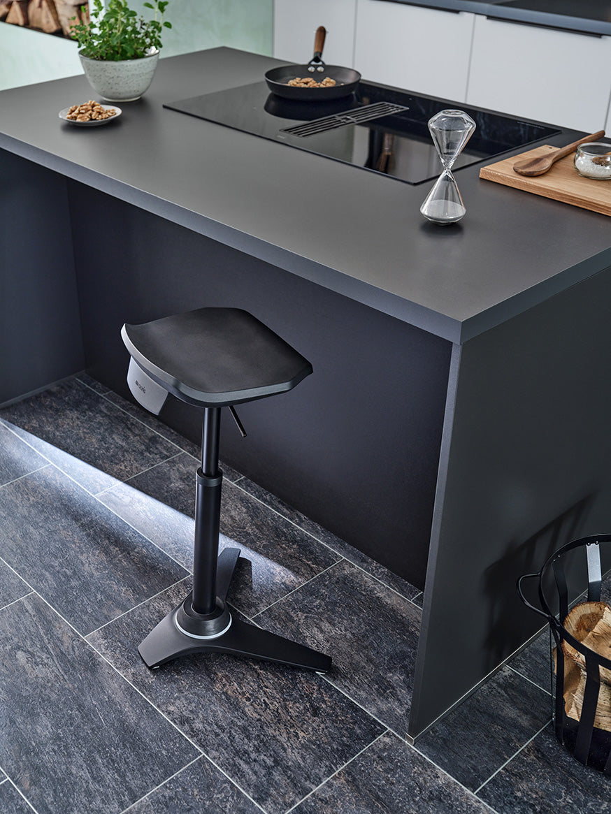 Black Muvman industry active stool at a dark kitchen island counter