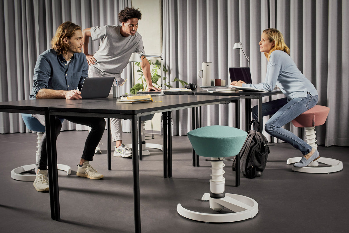 Colleagues working at a table on Swopper active chairs in an office
