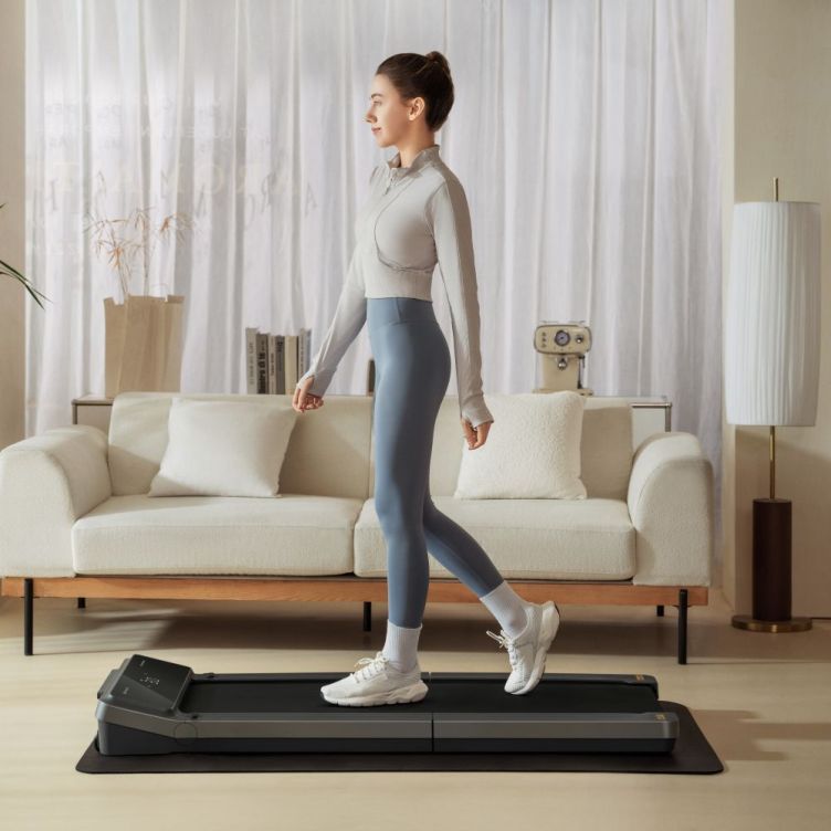 Woman walking on a WalkingPad V2 treadmill in a bright living room