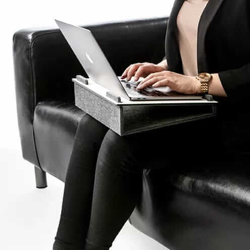 Person working on a laptop supported by a Lapsteri stand in an armchair