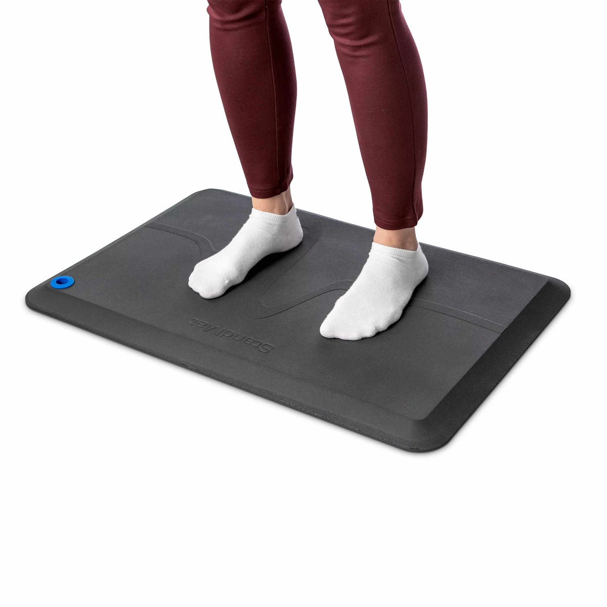 Person in socks standing on a black StandMat workstation mat