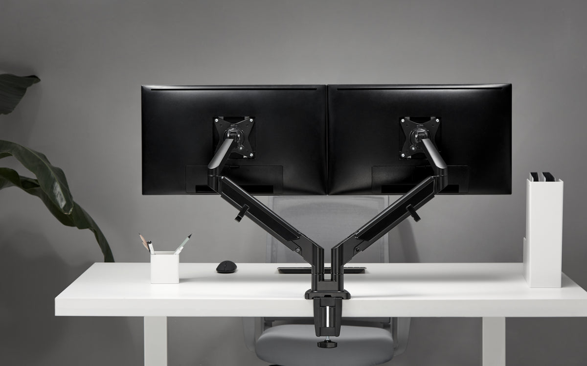 Desk with two curved monitors mounted on a black dual monitor arm