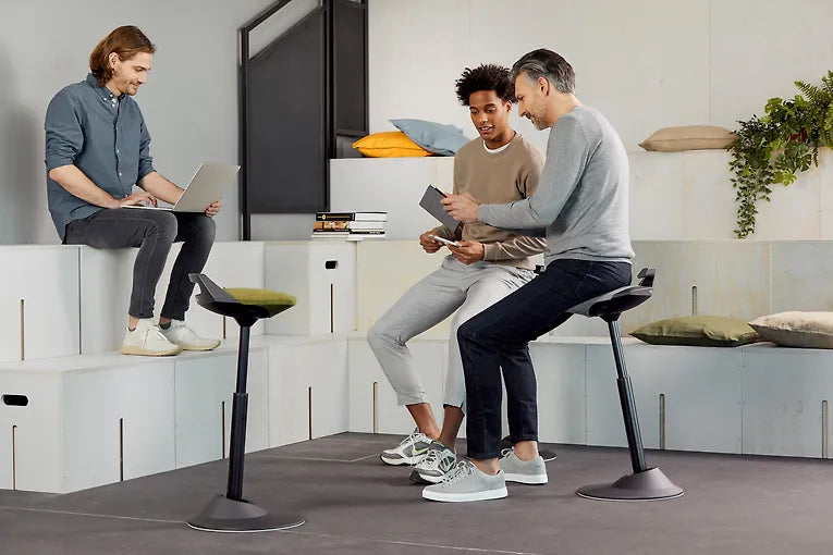 Colleagues talking in an office while using Muvman active standing stools