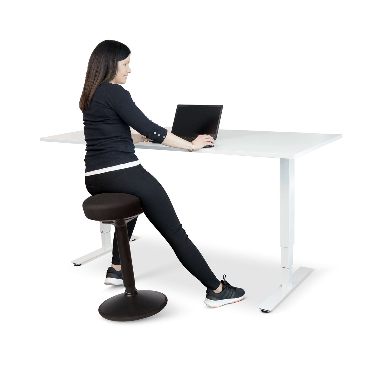 Woman using FitSit activity chair at adjustable desk, promoting ergonomic posture with black fabric seat.