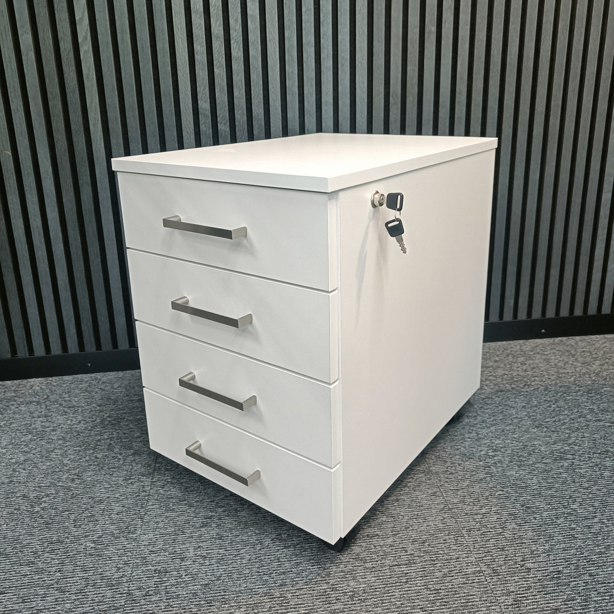 White four-drawer pedestal unit on castors, viewed at an angle