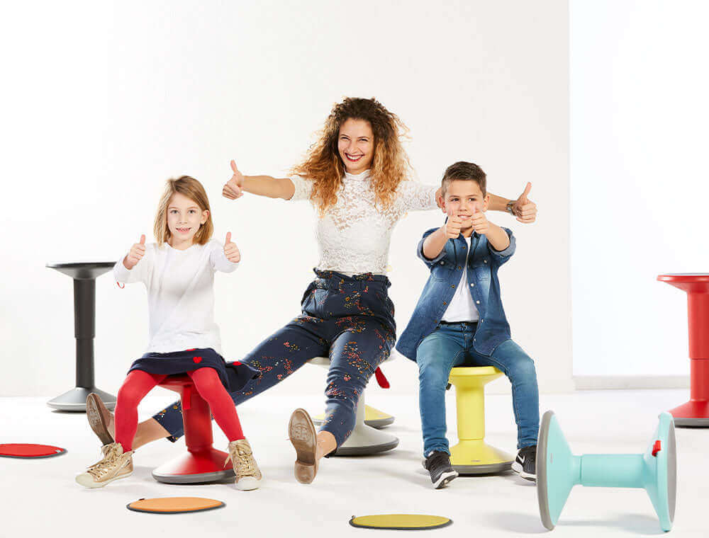 Three children posing with UPis1 active chairs in bright colours