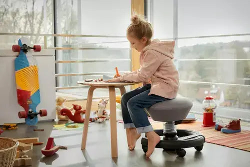 Child seated on a Swoppster active chair at a table in a playroom
