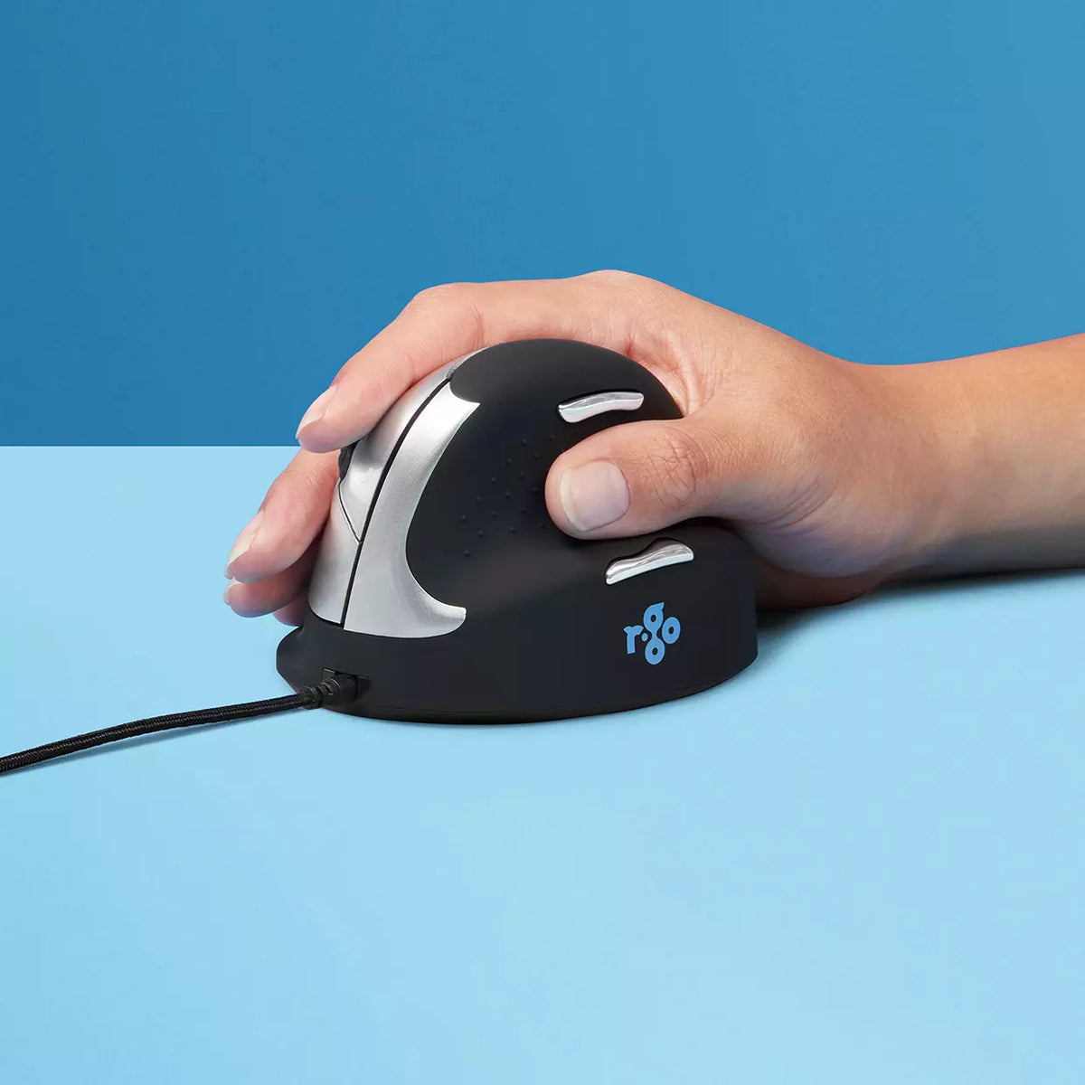 Hand gripping the HE Mouse vertical mouse against a blue background