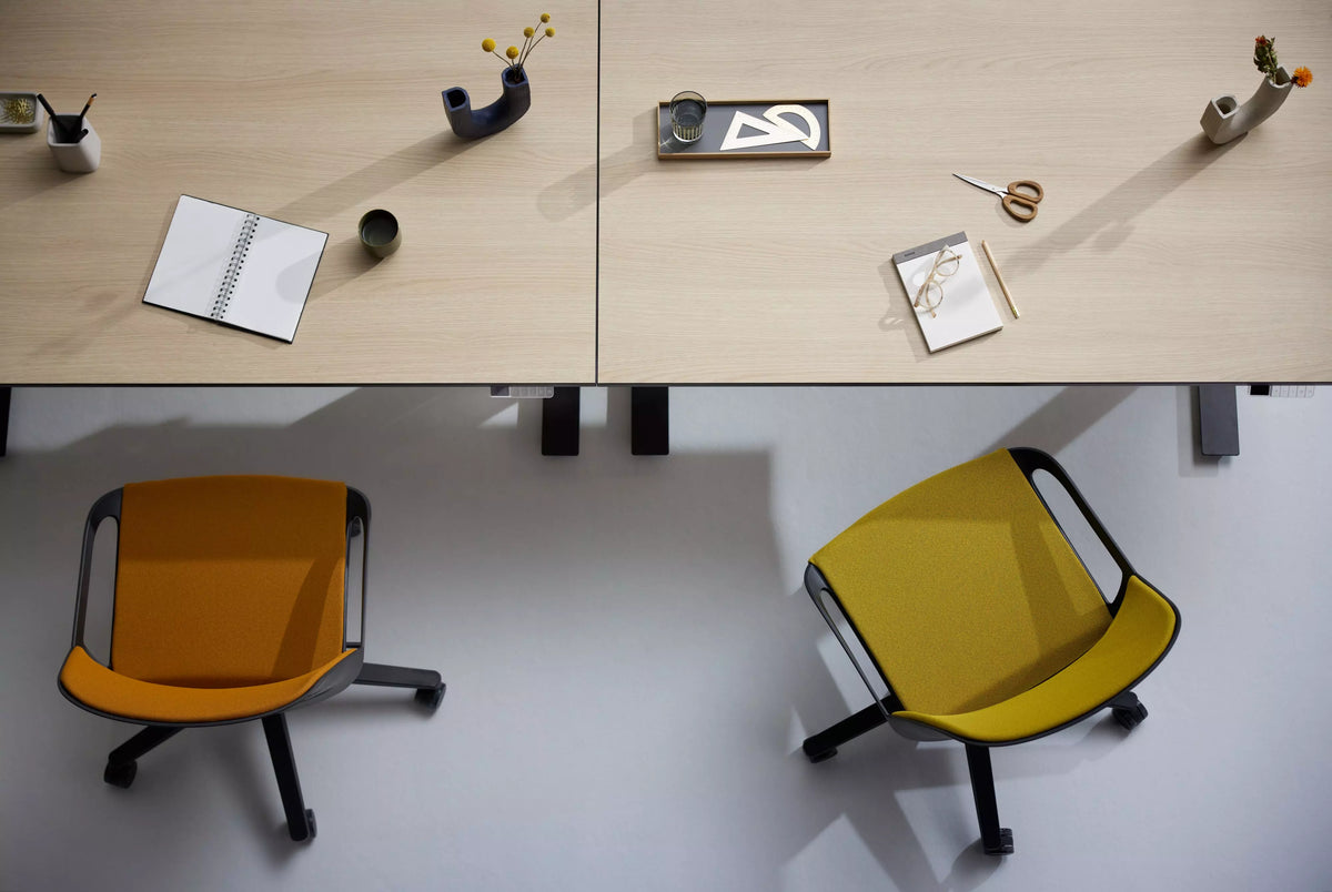 Office desks seen from above with orange and yellow Numo Task active chairs