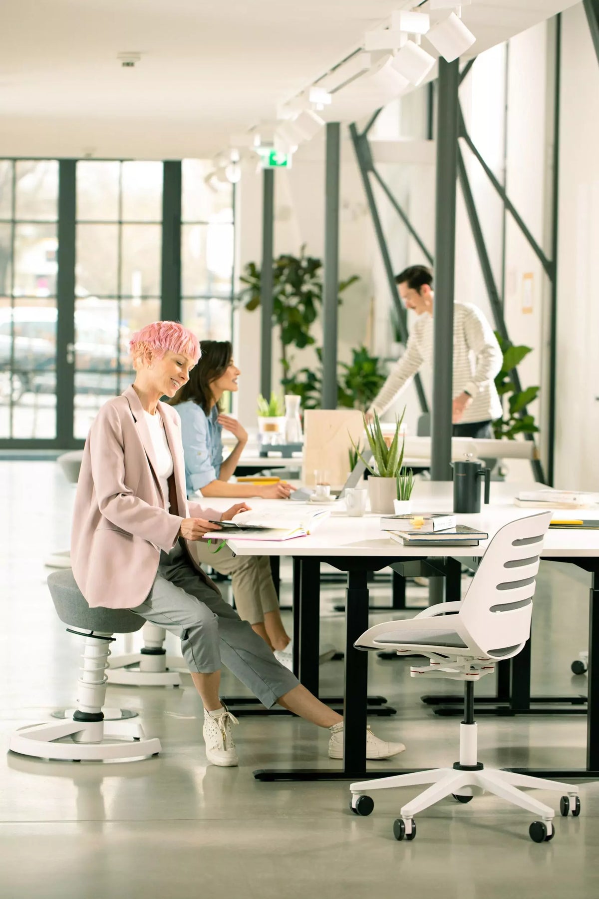 Woman working at a desk on a Numo Task active chair in a plant-filled office