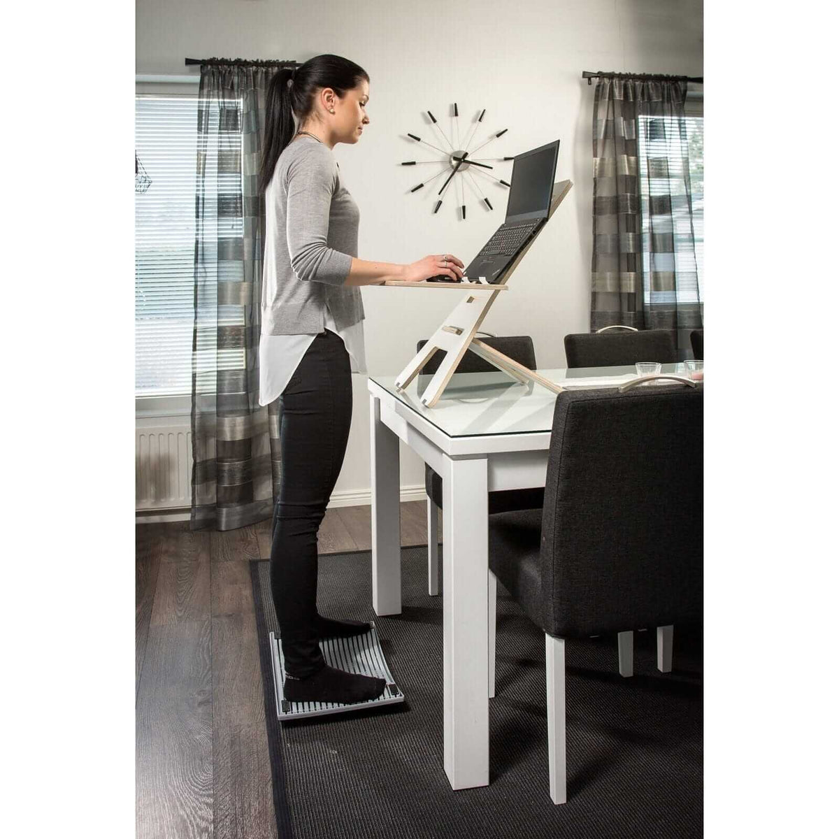 Woman using Gymbailu activation board at standing desk for improved concentration and movement in home office setting.